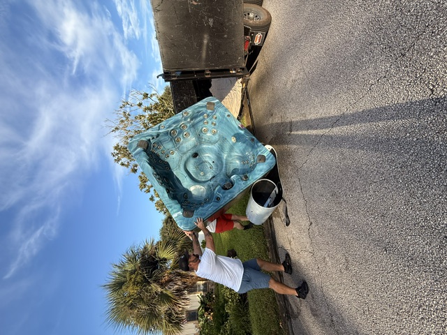 The Salty Dawgs crew moving a hot tub toward a hauling trailer.