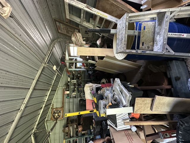 A garage filled with tools, shelving and stored items before cleanout.