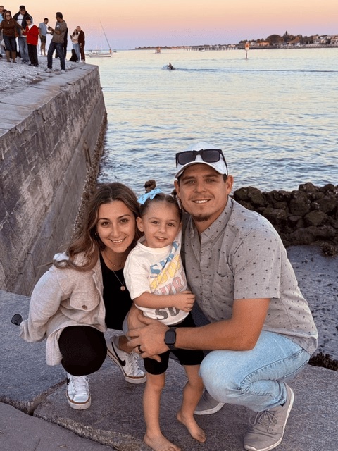 Maddie and Trevor with their child by the waterfront